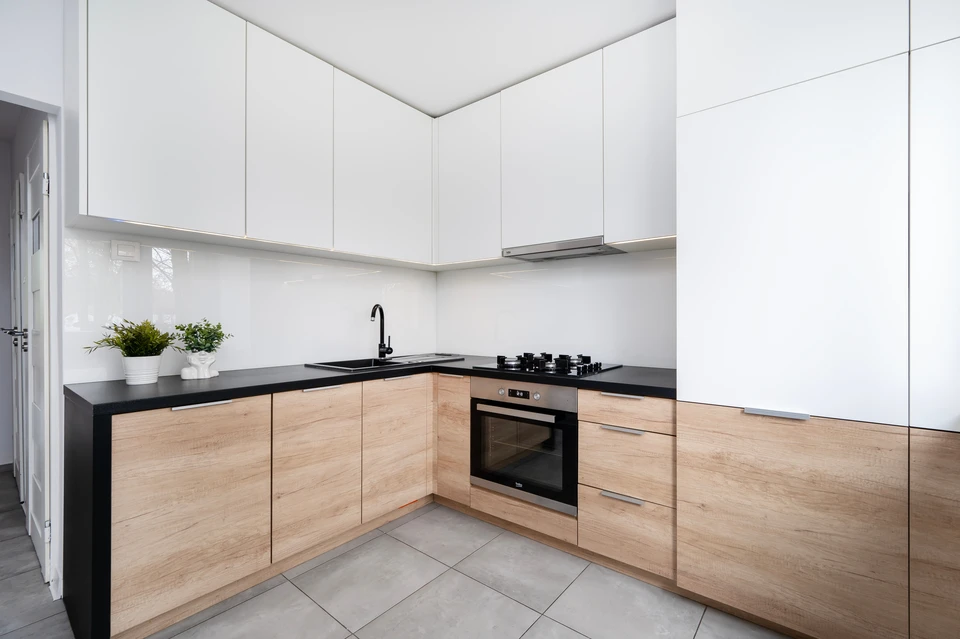 Cuisine moderne avec salle à mange intégrée, six chaises vertes autour d'une table blanche, luminaire suspendu à globes multiples, grandes fenêtres cintrées apportant lumière naturelle